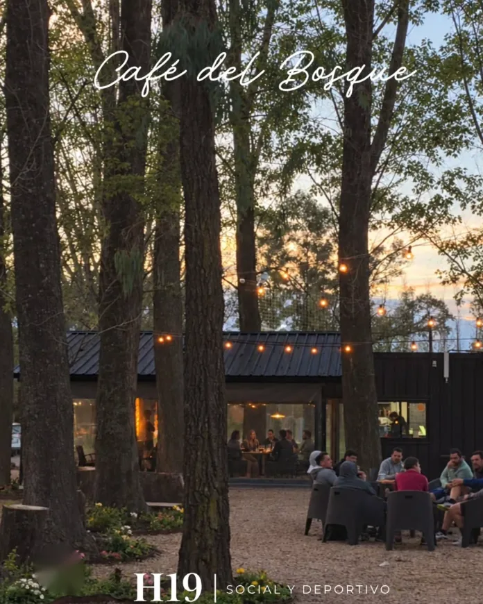 Café del Bosque en Hoyo 19 al atardecer, con gente en las mesas entre los árboles