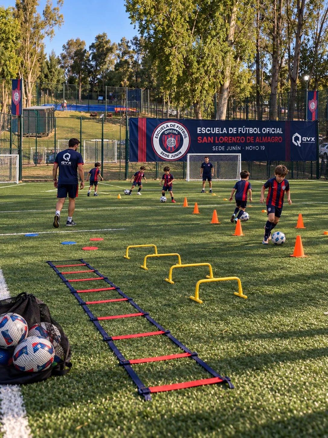 Chicos entrenando con la camiseta de San Lorenzo en el predio Hoyo 19, con el banner de la escuela de fondo